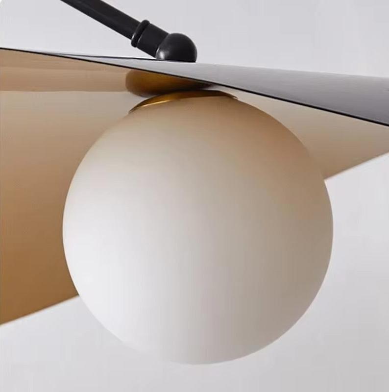 Black adjustable pendant light with a white globe and gold accents.