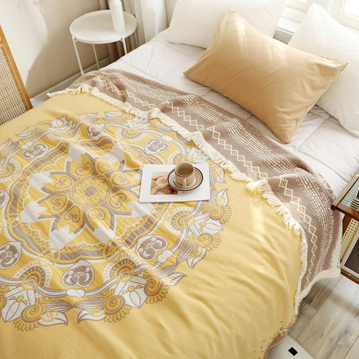 Yellow cotton boho mandala blanket with fringe detail on a bed.