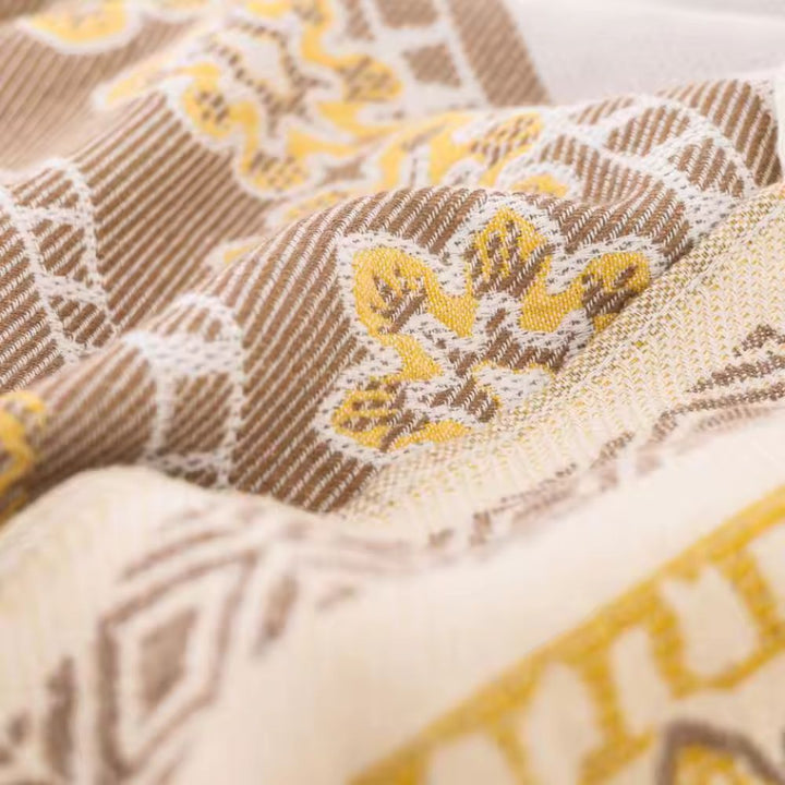 Close-up of a woven cotton blanket with a boho mandala pattern in brown and yellow.