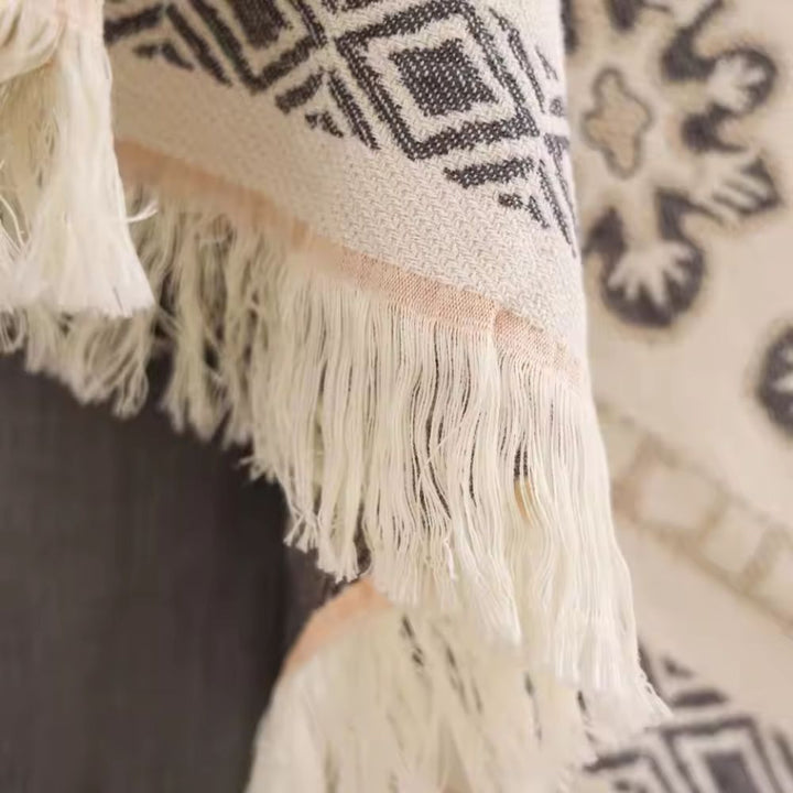 Close-up of a cream-colored cotton blanket with a boho mandala pattern and white fringe.