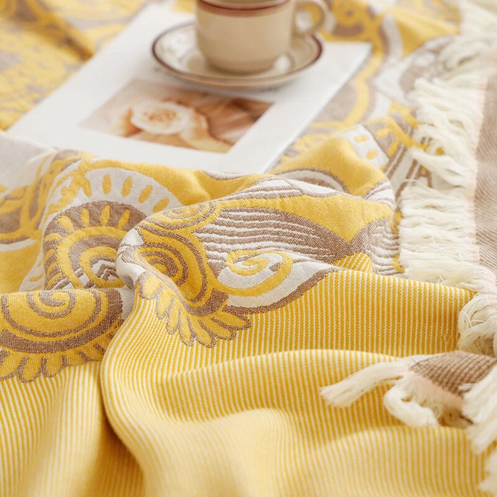 A close-up of a yellow cotton boho mandala blanket with fringe.