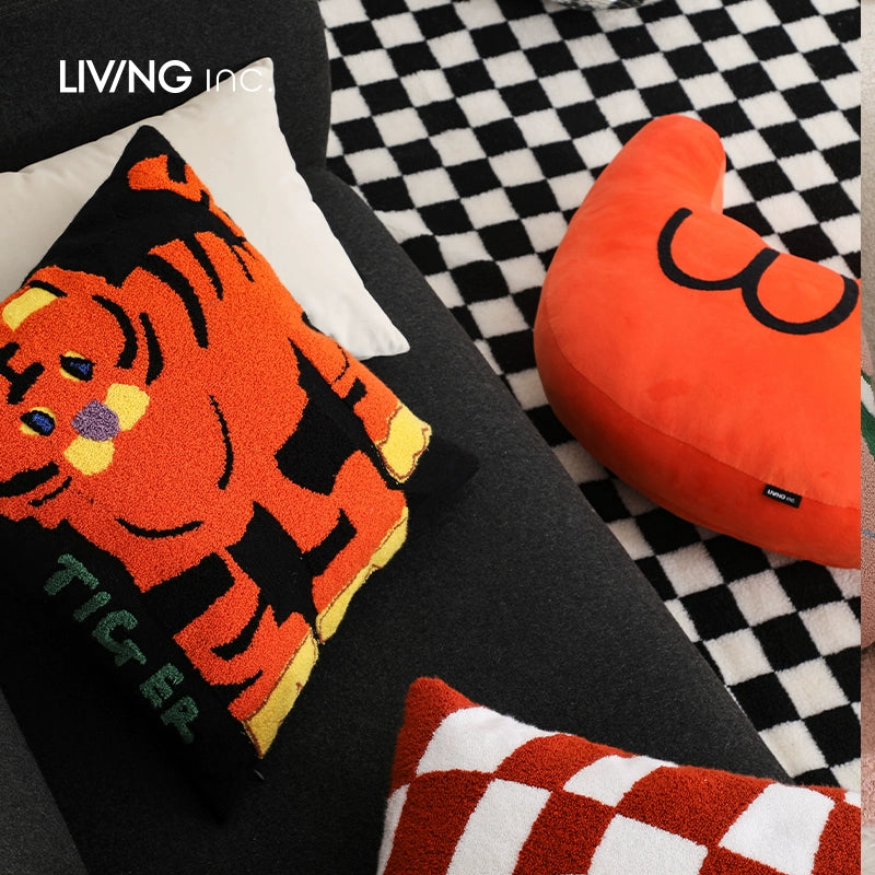 Orange tiger throw pillow with black stripes and yellow accents on a dark gray sofa.