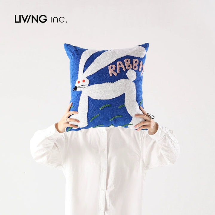 Blue pillow with a white rabbit and the word RABBIT in pink letters.
