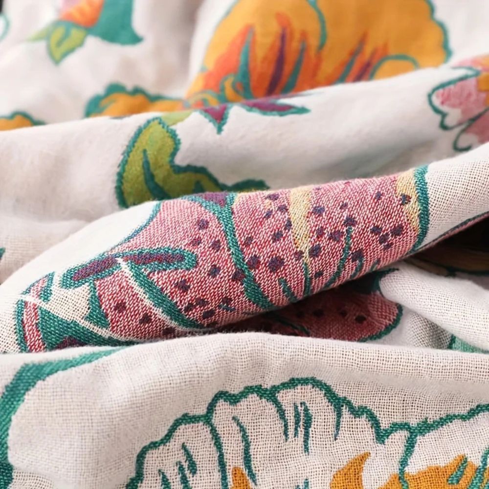 Close-up of a white cotton blanket with a colorful wildflower botanical print in pink, green, and orange.