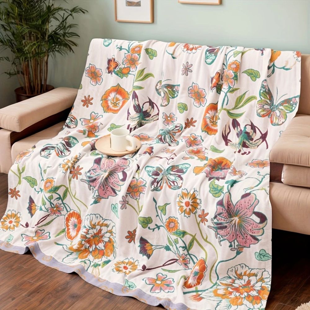 White cotton blanket with a colorful wildflower and butterfly print, draped over a sofa.