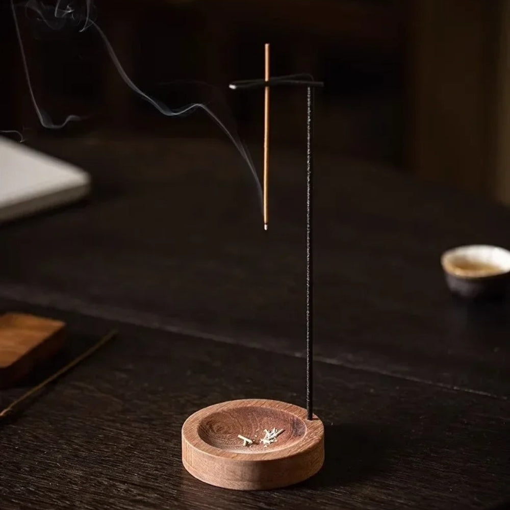 Minimalist wooden incense burner with a metal holder and a lit incense stick emitting smoke.