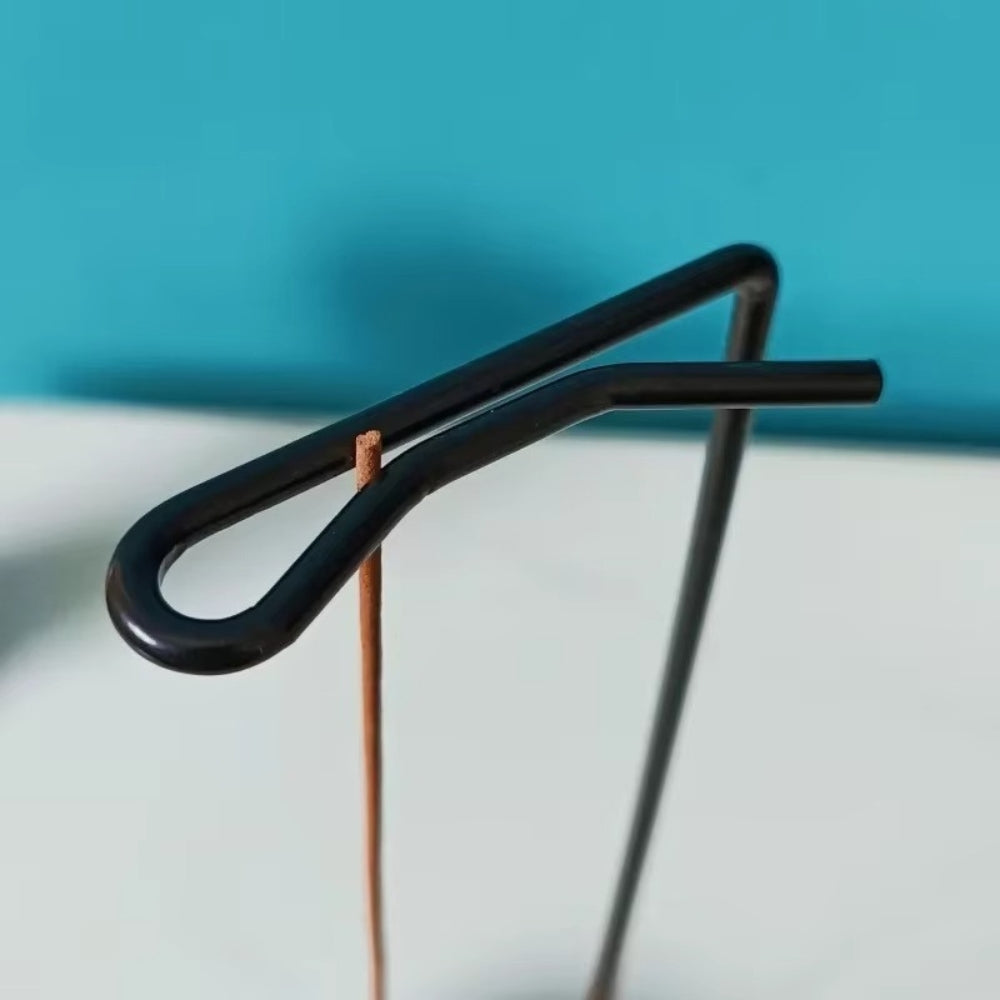 Minimalist black metal incense holder with a wooden base, designed for incense sticks.
