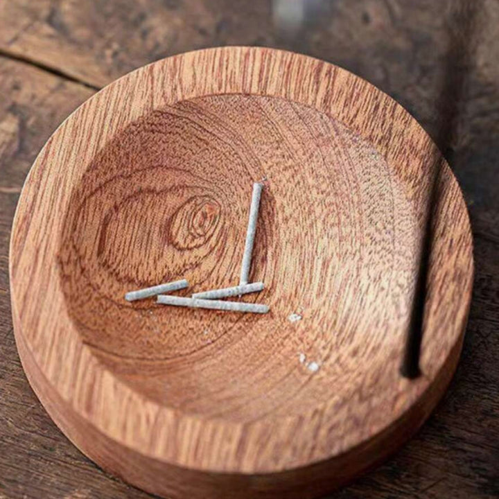 Wooden incense burner with a metal insert holding several incense sticks.