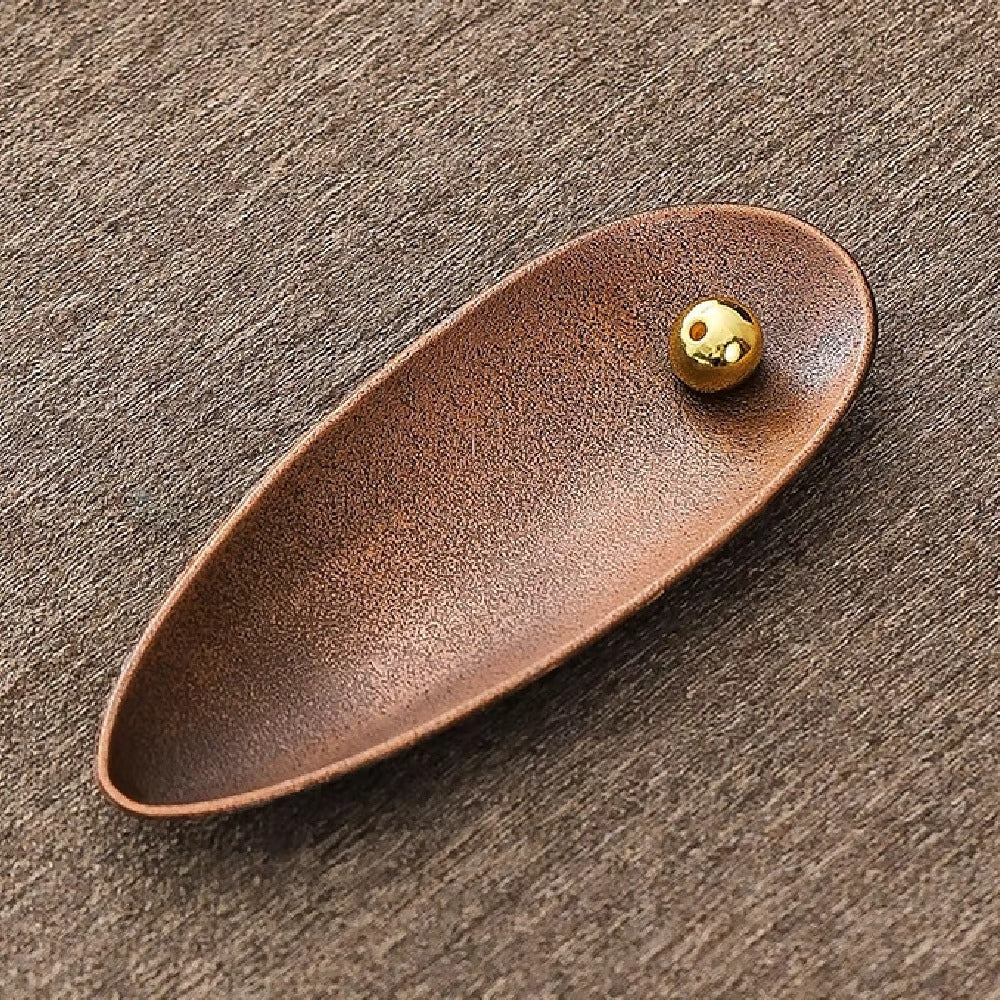Zen Alloy Bead Incense Holder with a golden bead on a textured brown surface.