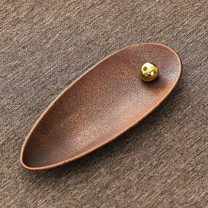 Zen Alloy Bead Incense Holder with a golden bead on a textured brown surface.