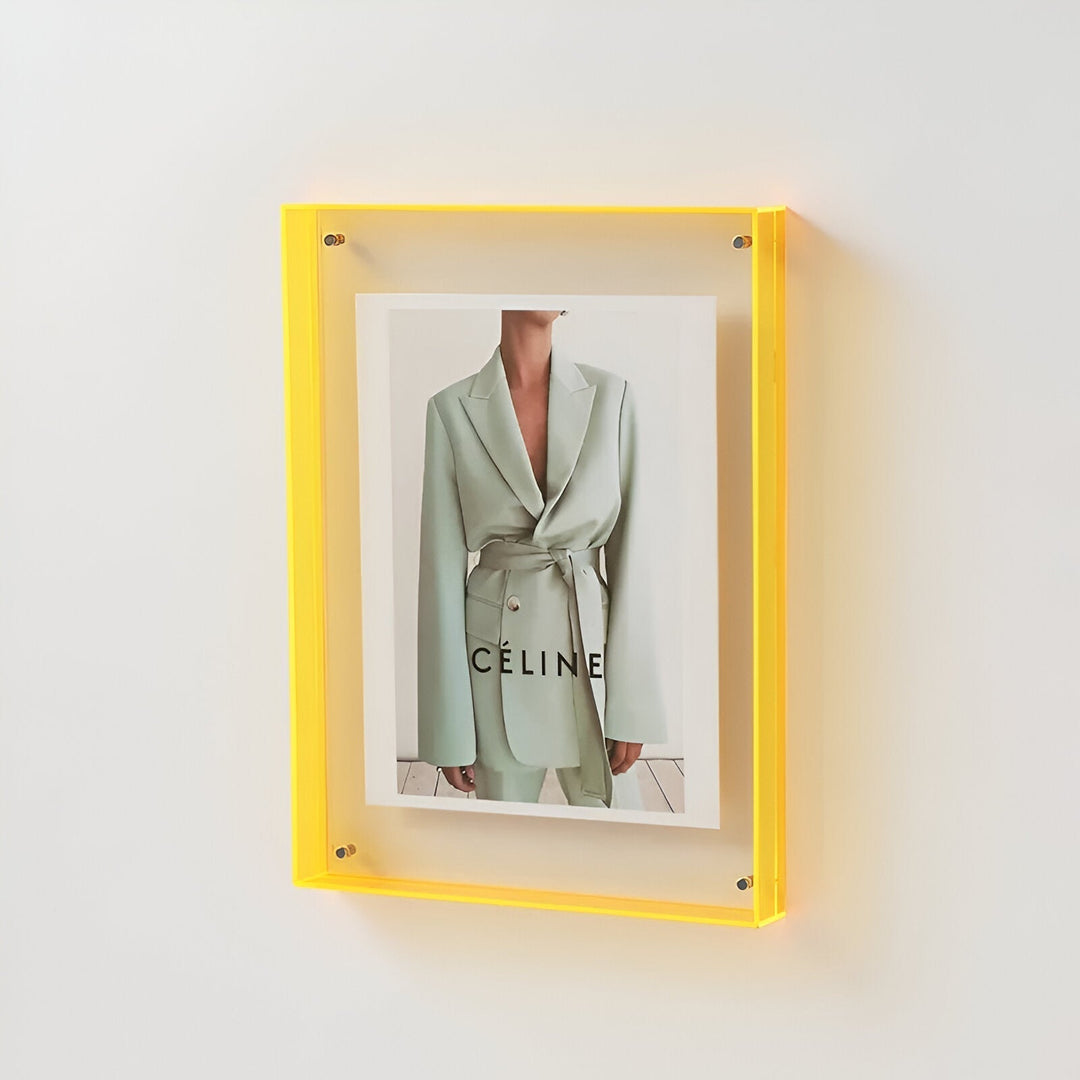 Yellow acrylic picture frame displaying a fashion ad with a light green suit and the word CELINE.