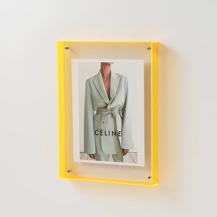Yellow acrylic picture frame displaying a fashion ad with a light green suit and the word CELINE.