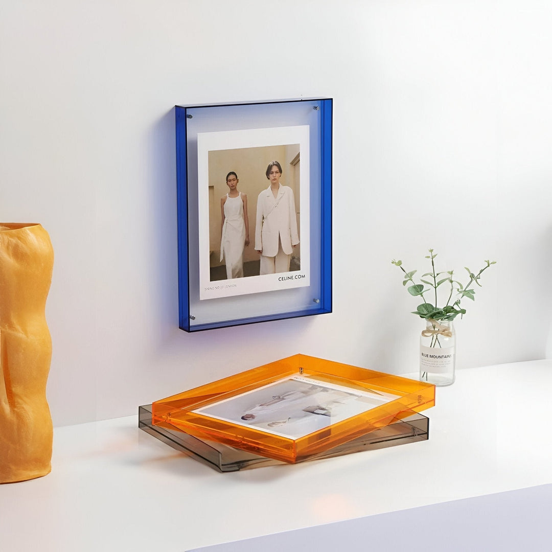 Blue and orange acrylic picture frames displaying fashion photos on a white surface.