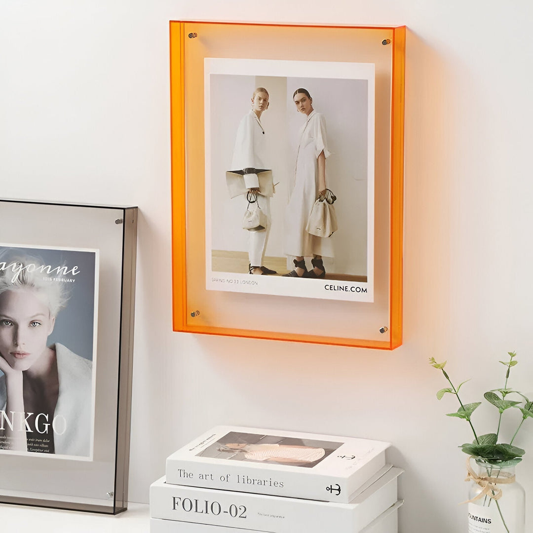 Orange acrylic picture frame displaying a fashion ad with two models.