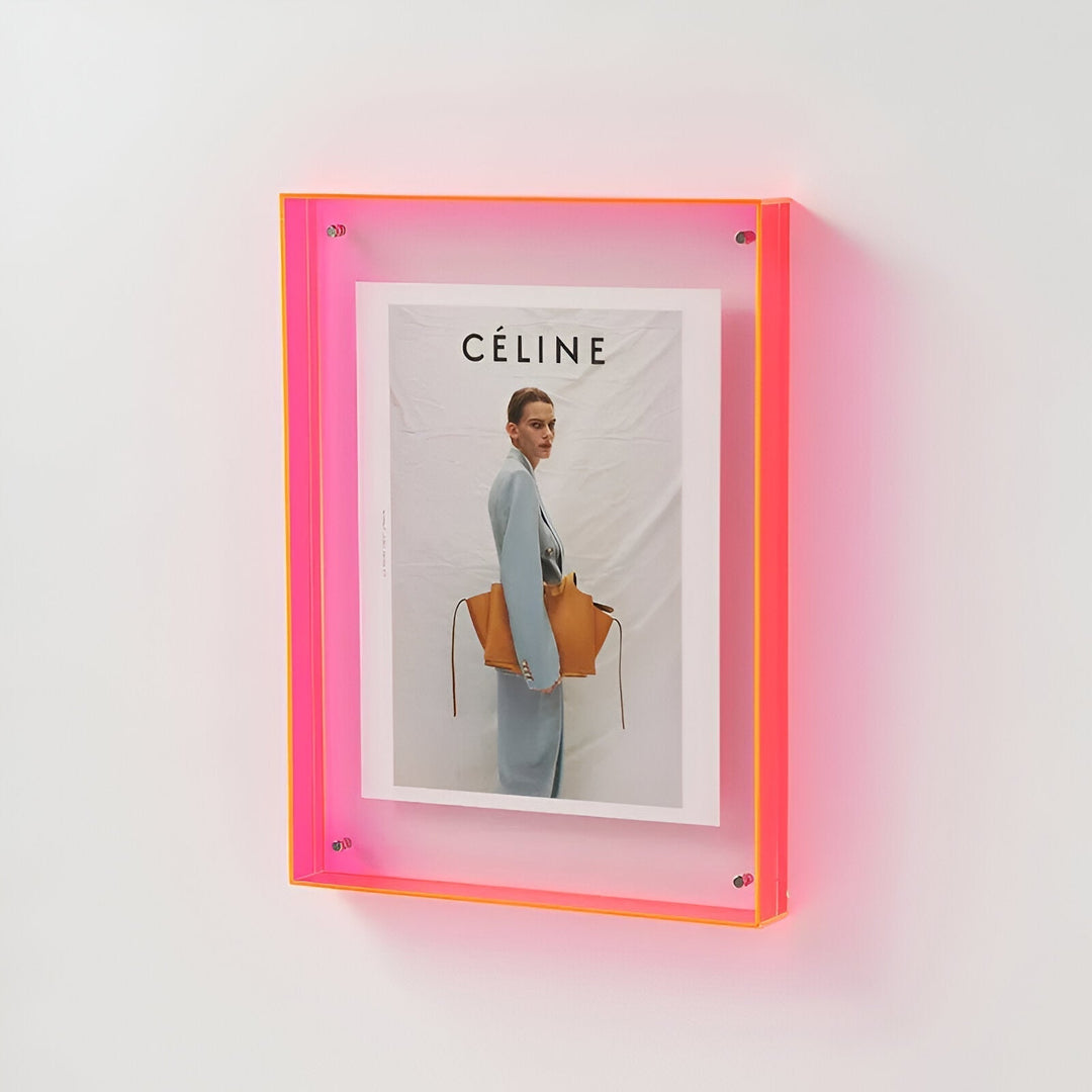 A neon pink and orange acrylic frame holding a Celine magazine cover with a model.