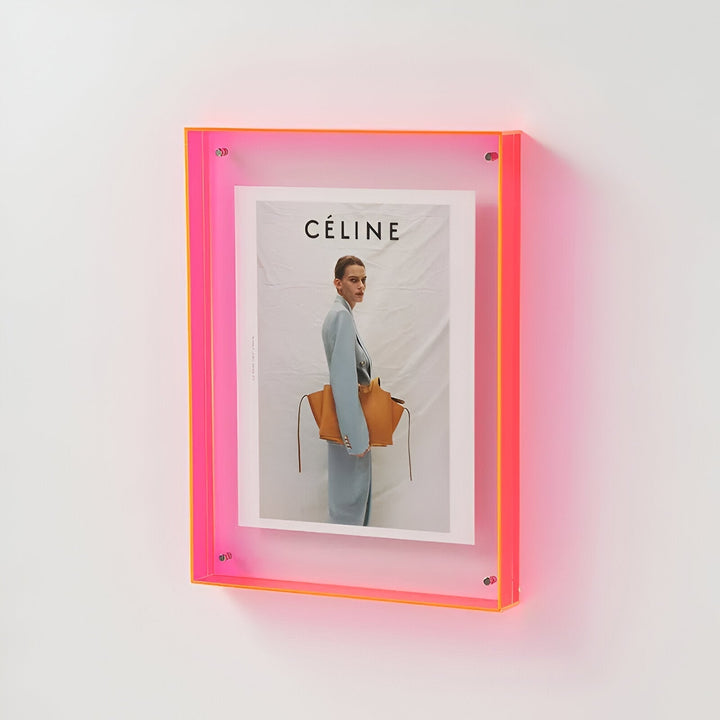 A neon pink and orange acrylic frame holding a Celine magazine cover with a model.