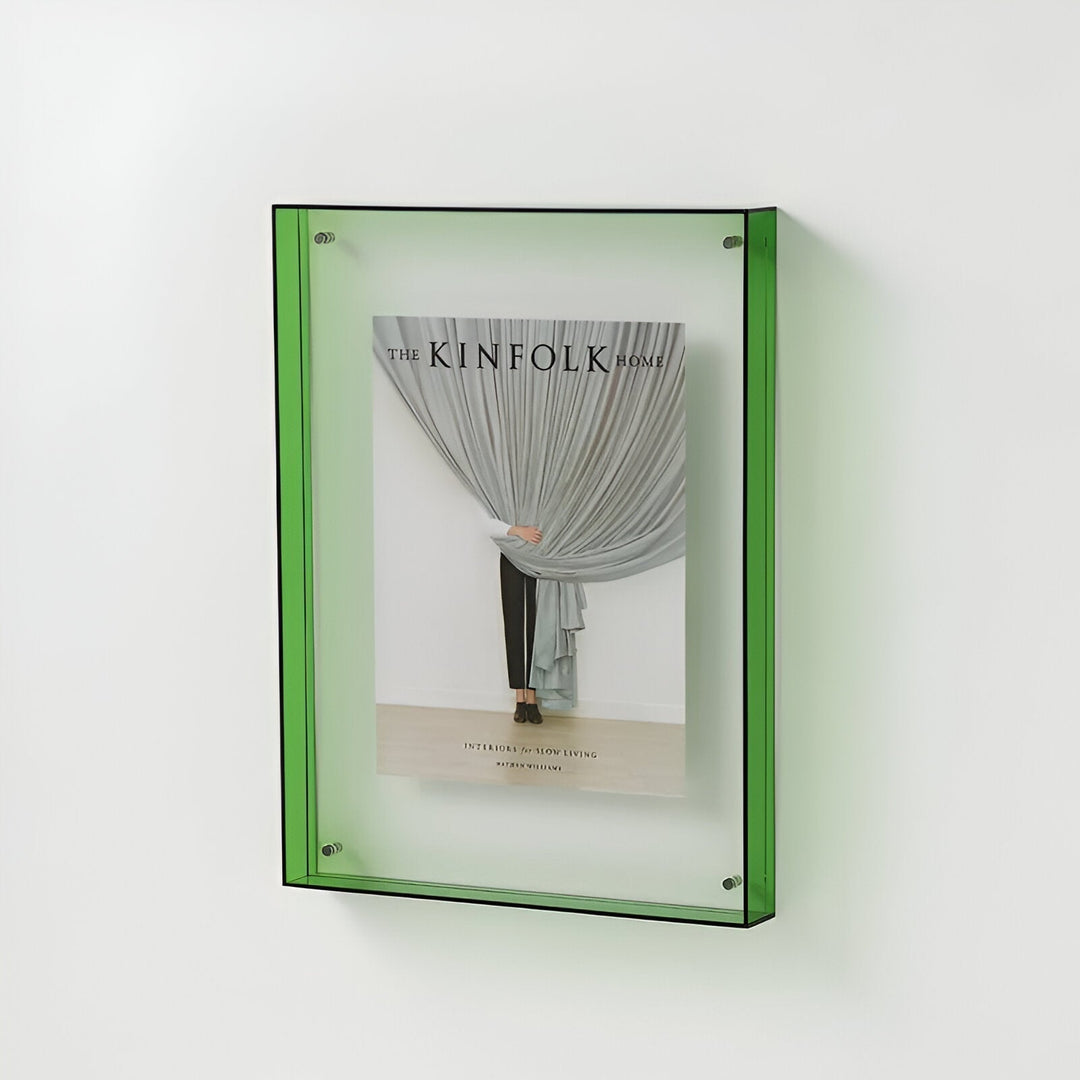 Green acrylic picture frame mounted on a white wall, displaying a magazine cover.
