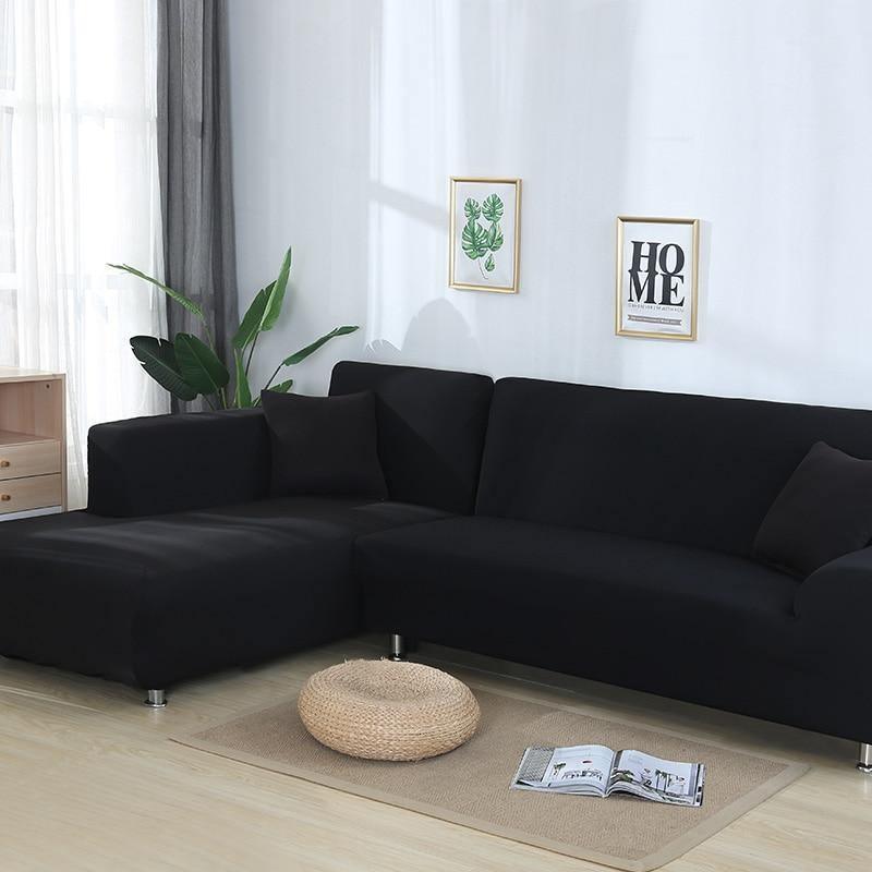 Black L-shaped sectional sofa cover with two throw pillows and a small round ottoman.