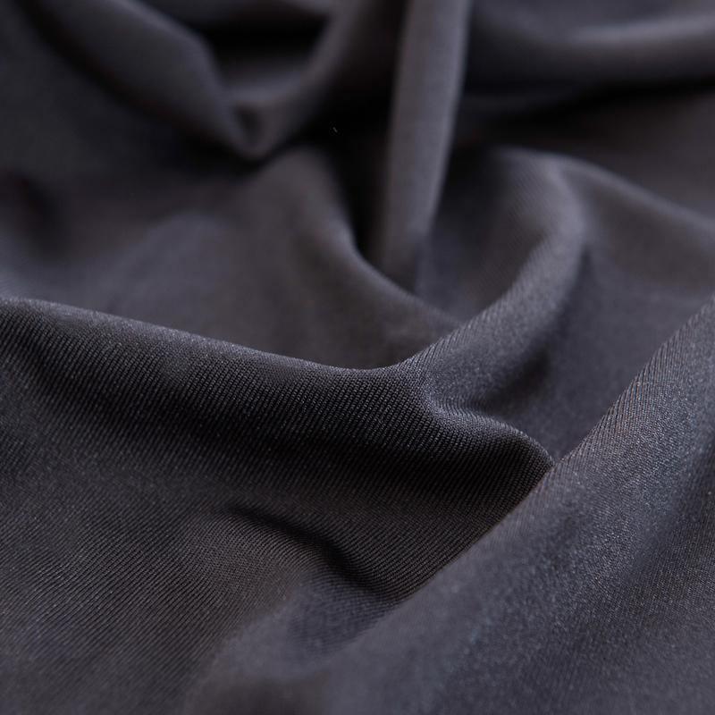 Close-up of a black L-shaped sofa cover with a matte micro-fabric finish and visible texture.