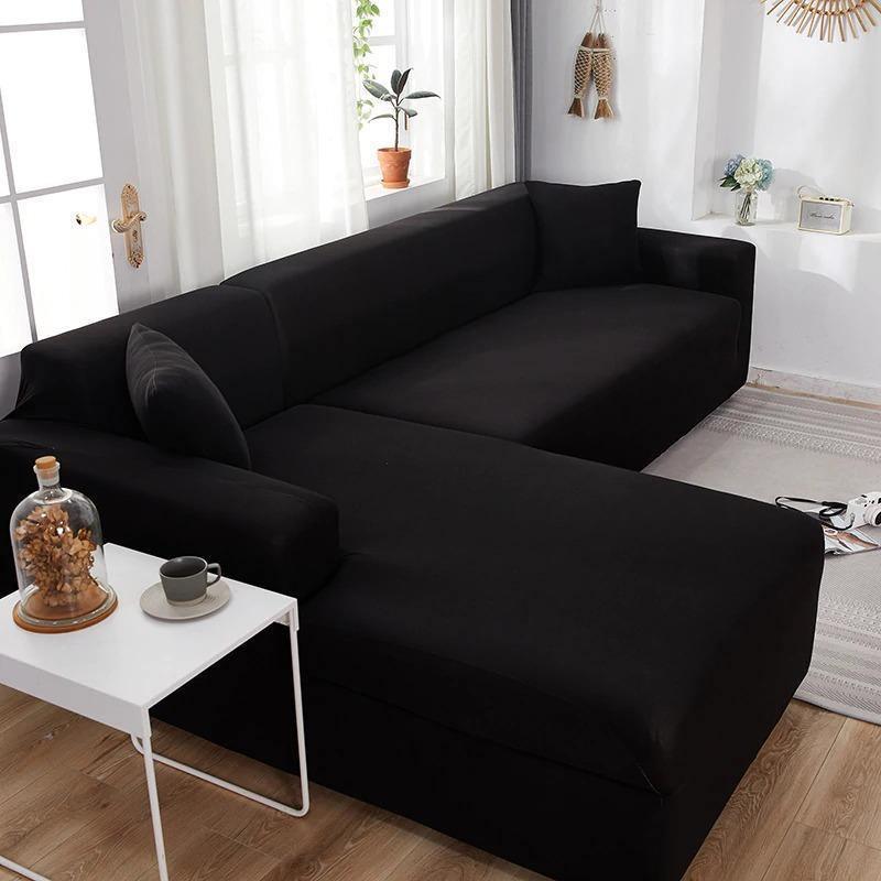 Black L-shaped sofa cover on a sectional sofa, with a small white table and a glass dome with dried flowers in front.