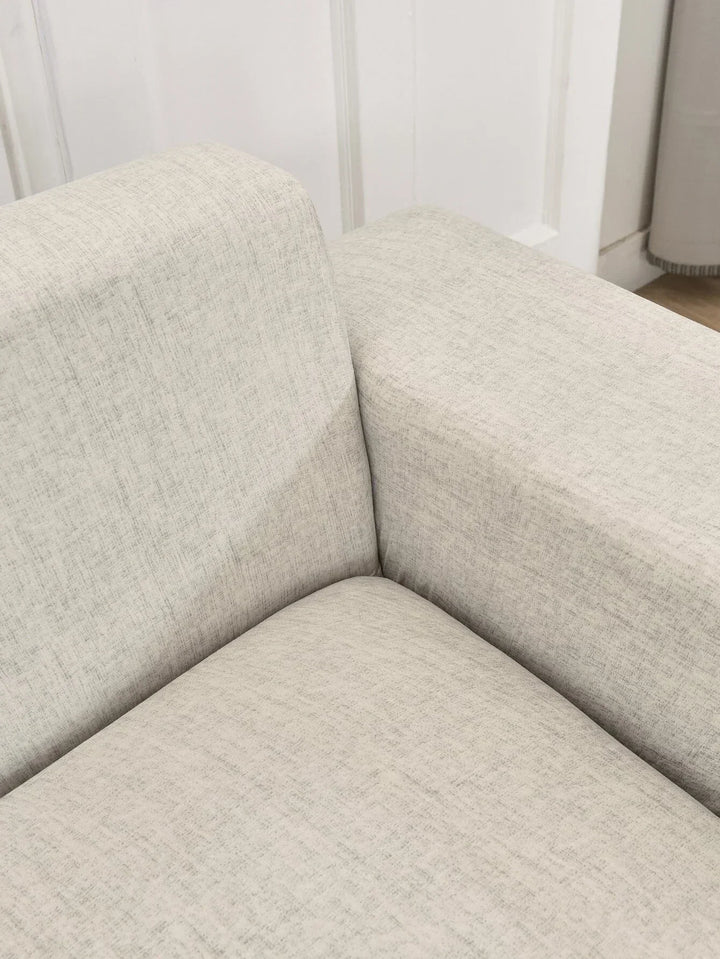 A close-up of an egg shell colored L-shaped sofa cover with a subtle cross-weave texture.
