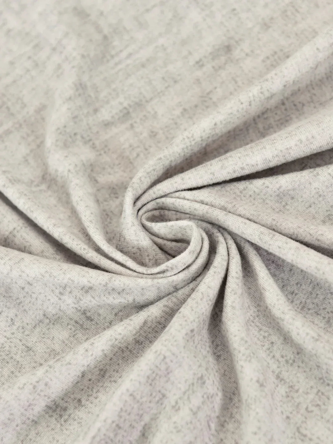 Close-up of a light grey, textured L-shaped sofa slipcover with a subtle cross-weave pattern.