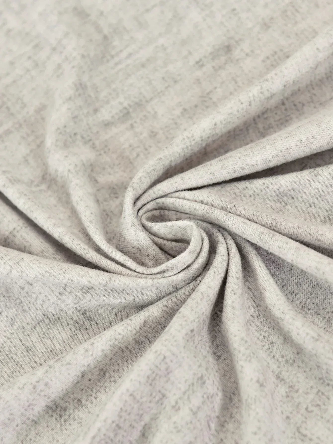 Close-up of a light grey, textured L-shaped sofa slipcover with a subtle cross-weave pattern.