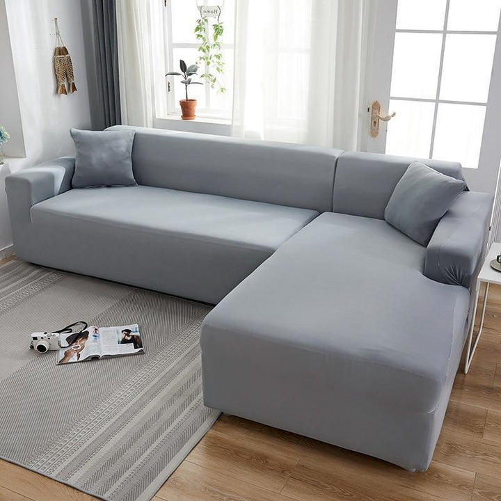 Mouse grey L-shaped sofa cover on a sectional couch with a pillow on each end.