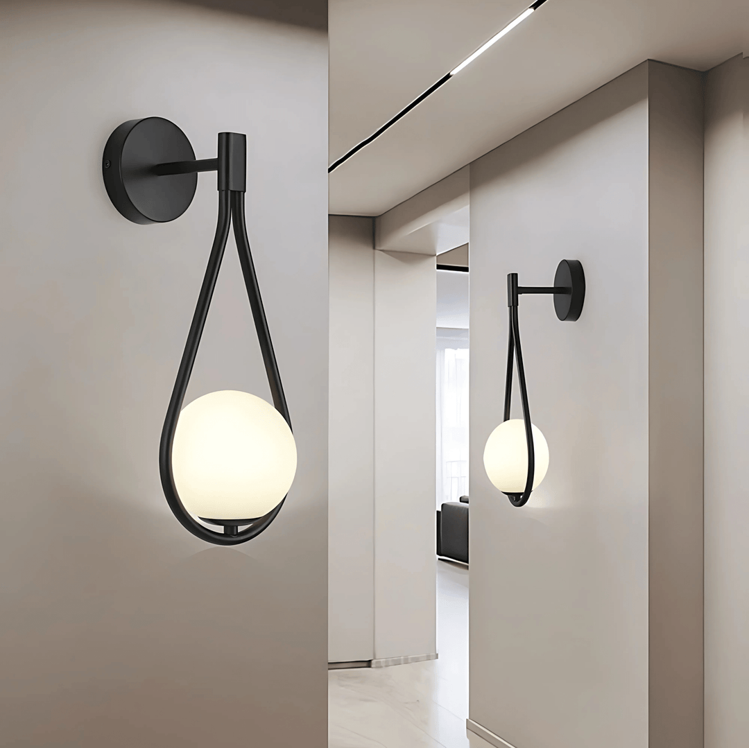 Black teardrop wall sconce with a frosted globe light, mounted on a light gray wall.