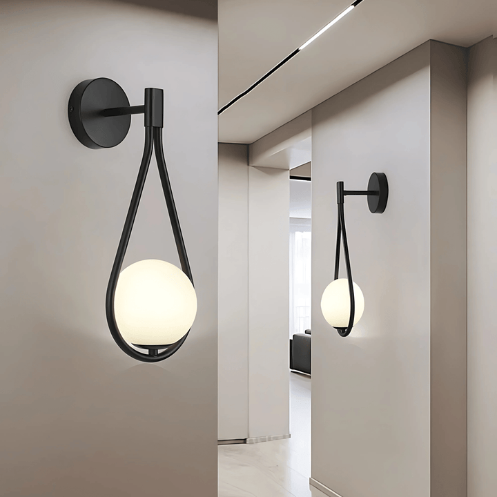 Black teardrop wall sconce with a frosted globe light, mounted on a light gray wall.