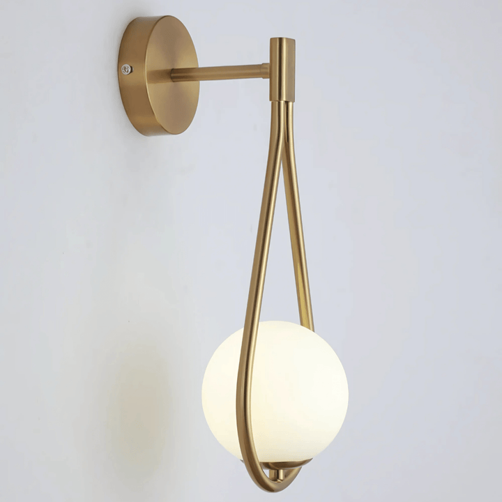 Brass teardrop wall sconce with a frosted white globe light against a white wall.