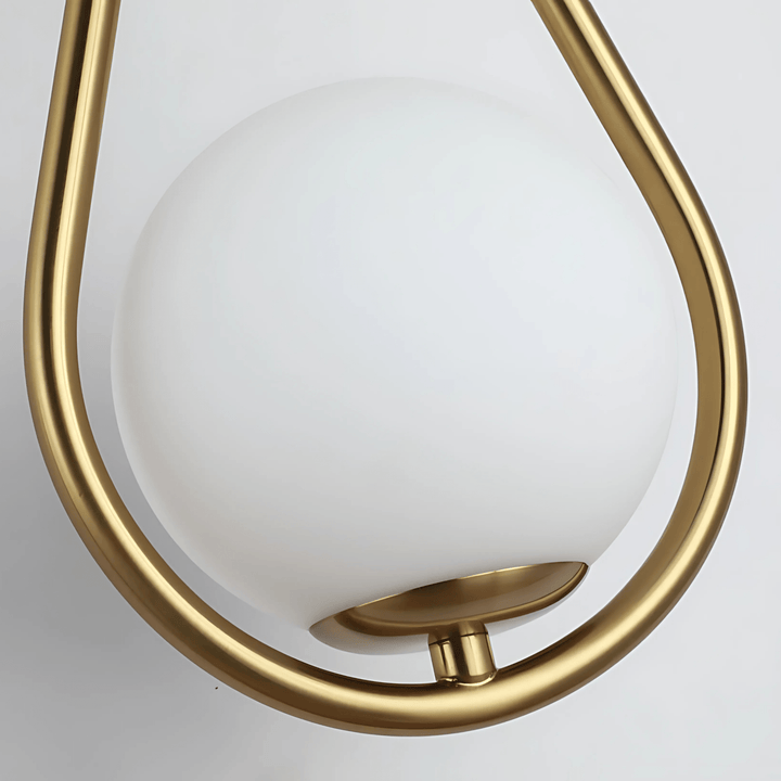 Gold teardrop wall sconce with a white globe light.