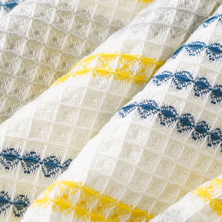 White honeycomb weave cotton bath towel with blue and yellow stripes.
