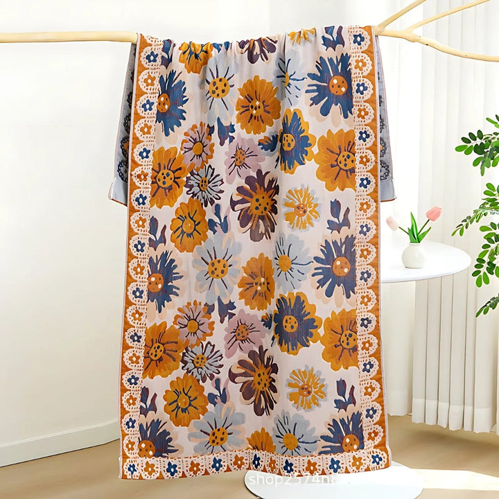 Reversible cotton bath towel with a vibrant floral print in blue, orange, and yellow on a light background.