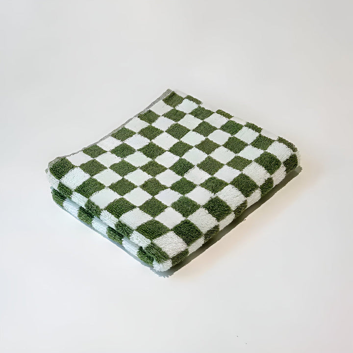 Green and white checkered cotton towel folded on a white surface.