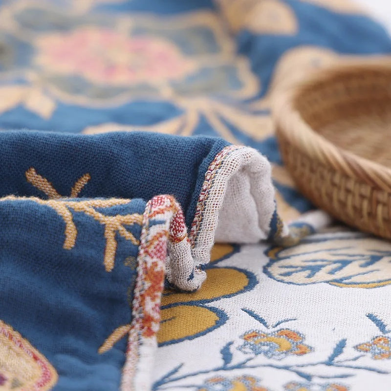 Blue cotton blanket with a rustic artistic floral pattern, folded to show edge detail.