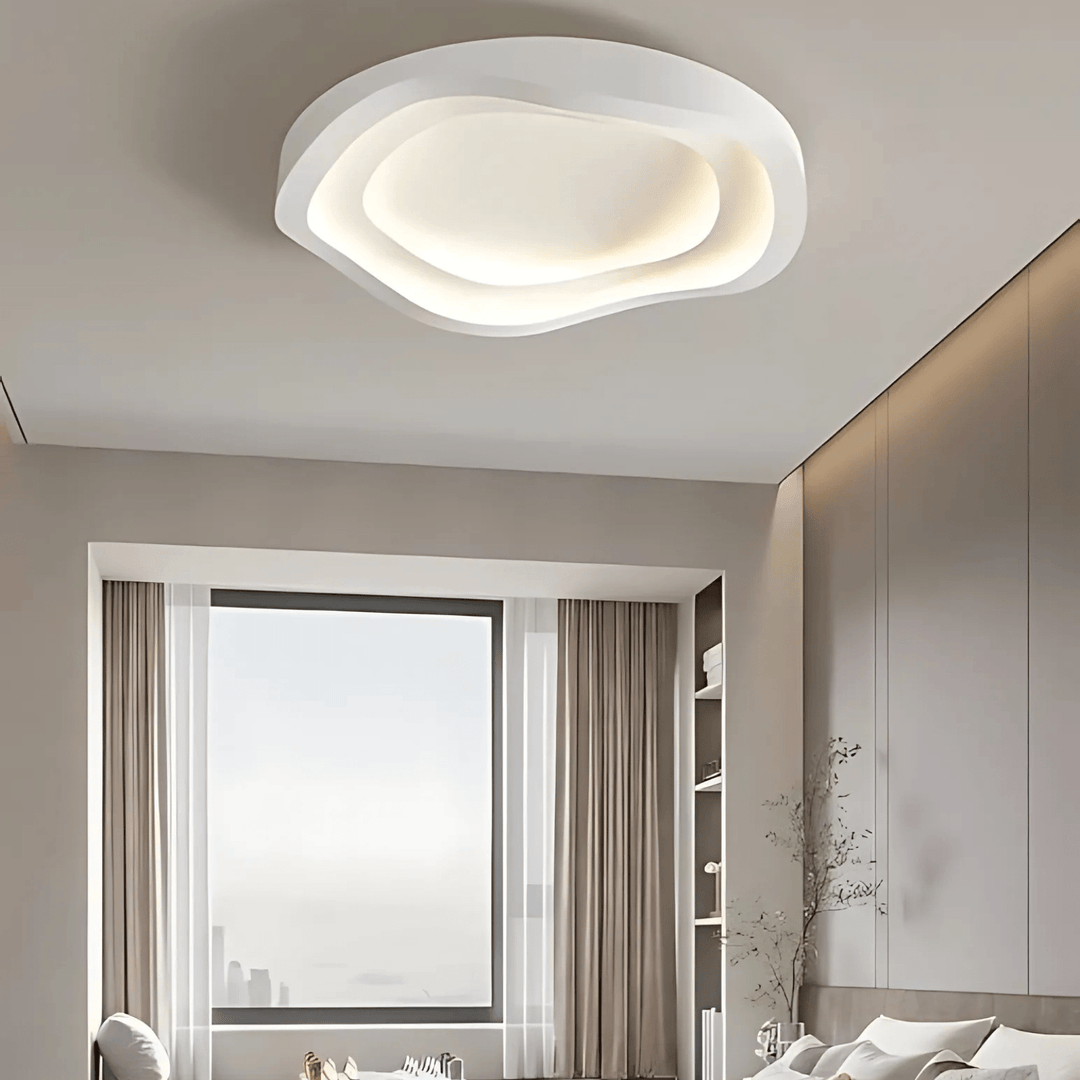 Modern white wavy layered ceiling light fixture illuminating a bedroom.