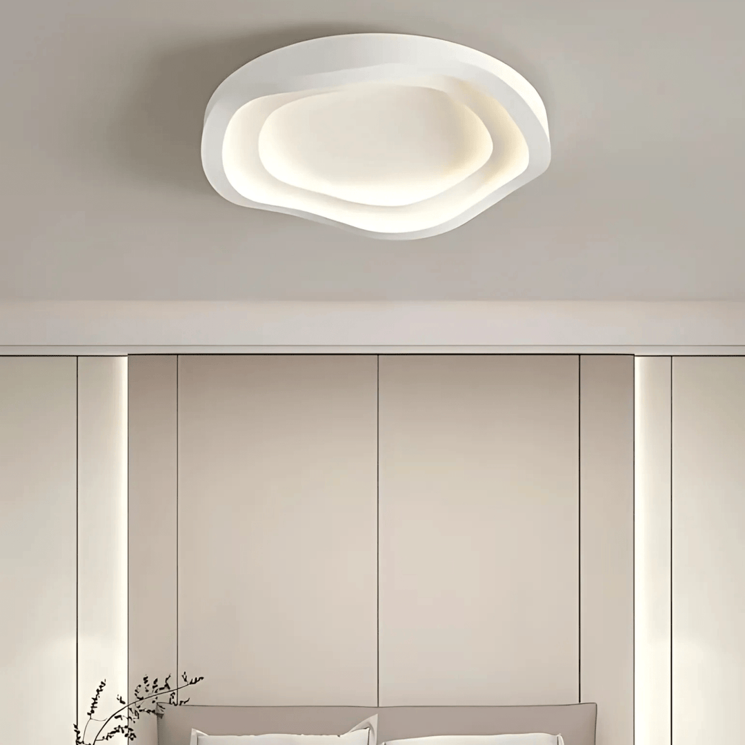 Modern white layered ceiling light with organic, wavy edges, casting a soft glow.