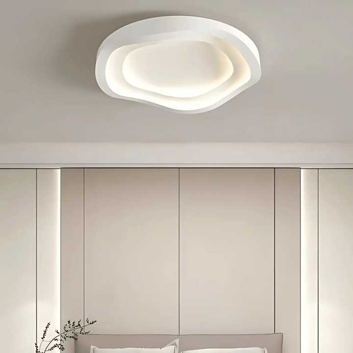 Modern white layered ceiling light with organic, wavy edges, casting a soft glow.