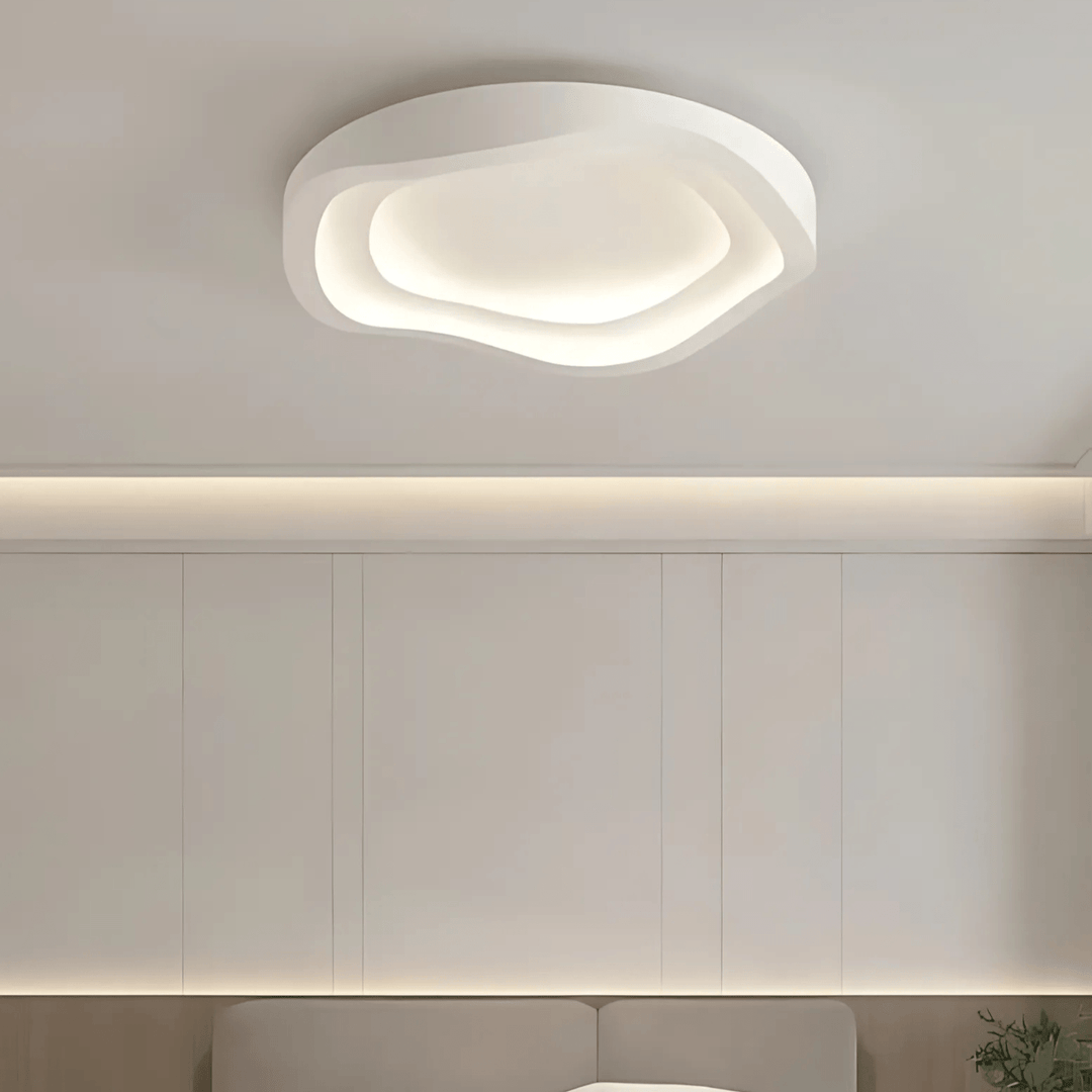 Modern white ceiling light with a layered, wavy design, illuminating a room.