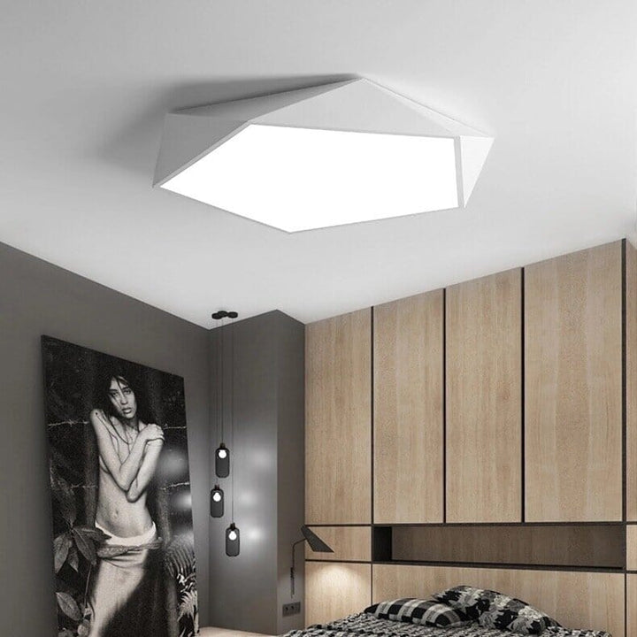 A modern white geometric ceiling light fixture mounted in a contemporary bedroom.