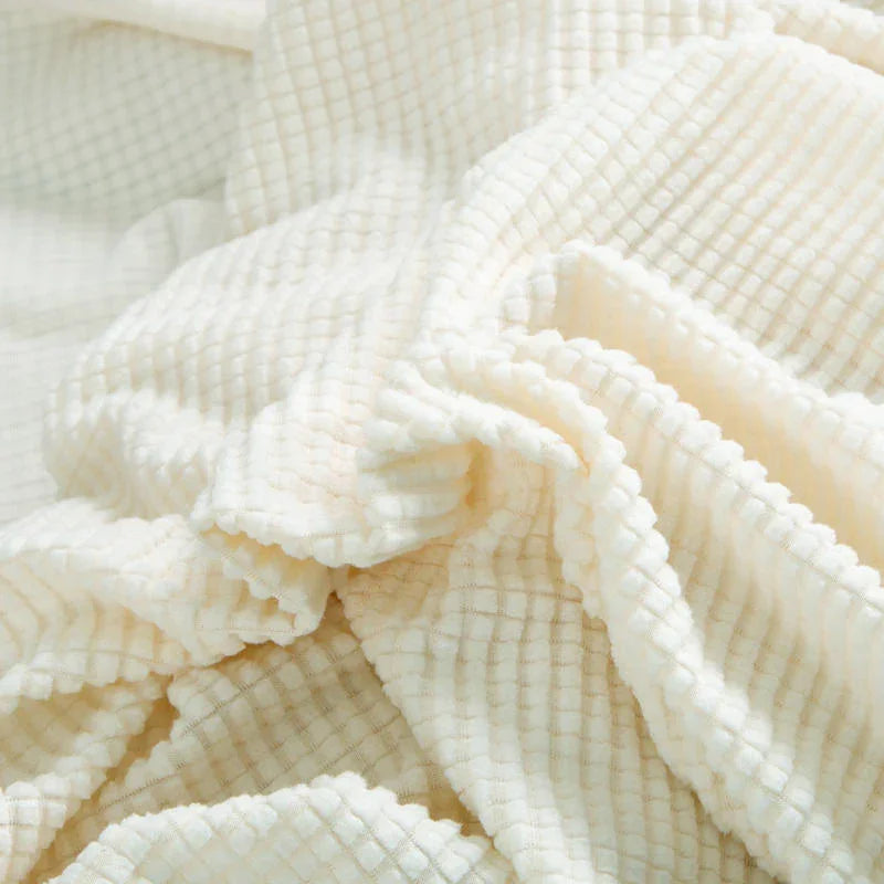 Close-up of a white jacquard couch cover with a subtle woven texture.