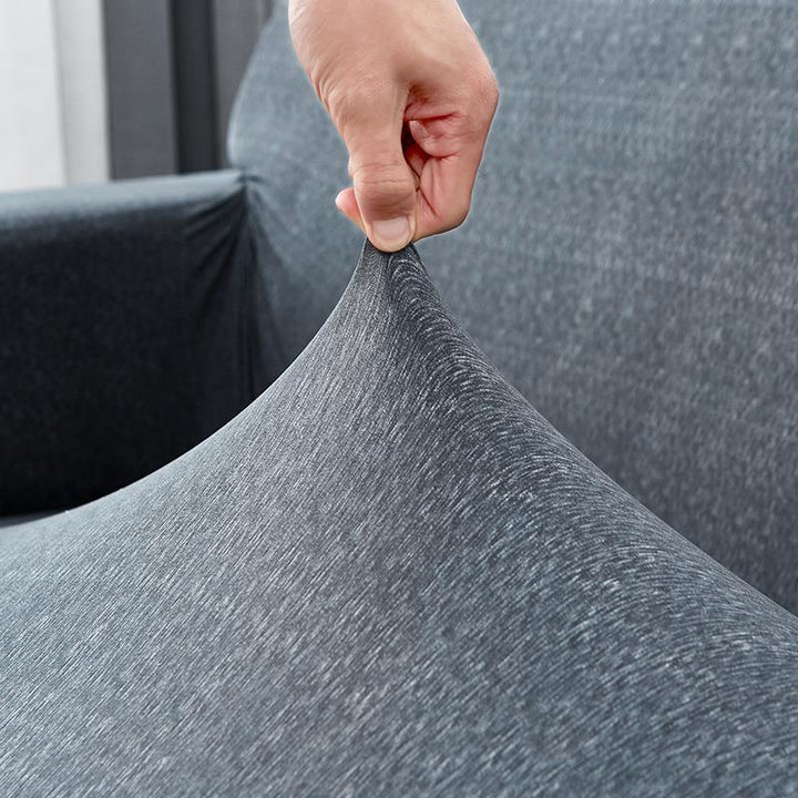 Hand stretching a grey spotted anthracite sofa cover to show its adaptable fit.
