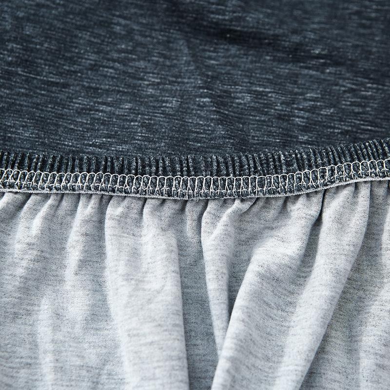 Close-up of a dark grey spotted L-shaped sofa cover showing the elasticized edge and fabric texture.