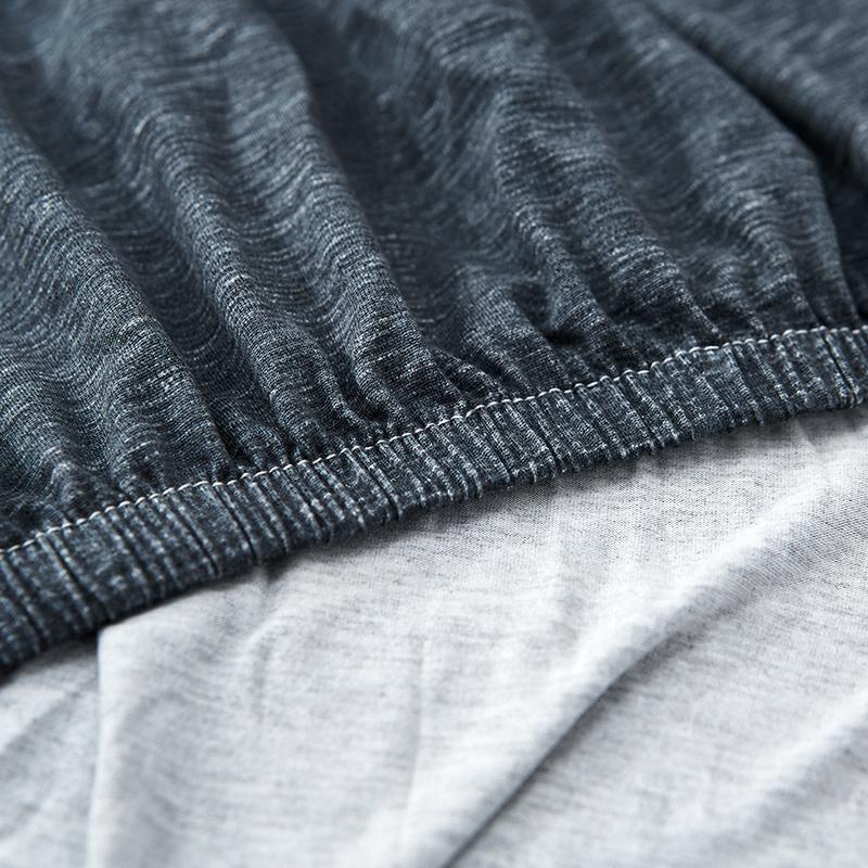 Close-up of a dark grey spotted L-shaped sofa cover with elasticized edge.
