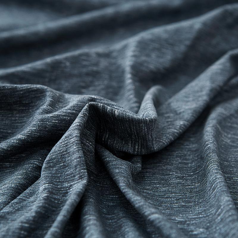 Close-up of a dark grey, textured fabric with subtle white speckles, showing soft folds and wrinkles.