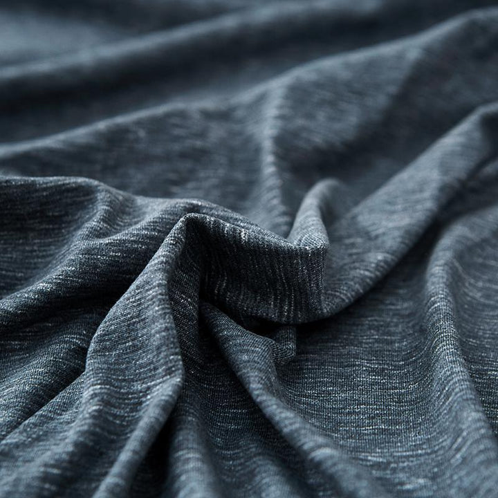 Close-up of a dark grey, textured fabric with subtle white speckles, showing soft folds and wrinkles.
