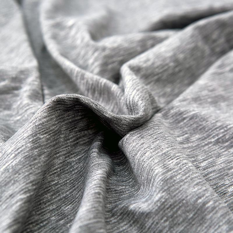 Close-up of a light grey, spotted L-shaped sofa cover with a textured weave.