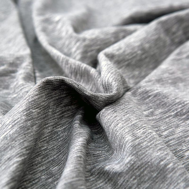 Close-up of a light grey, spotted L-shaped sofa cover with a textured weave.