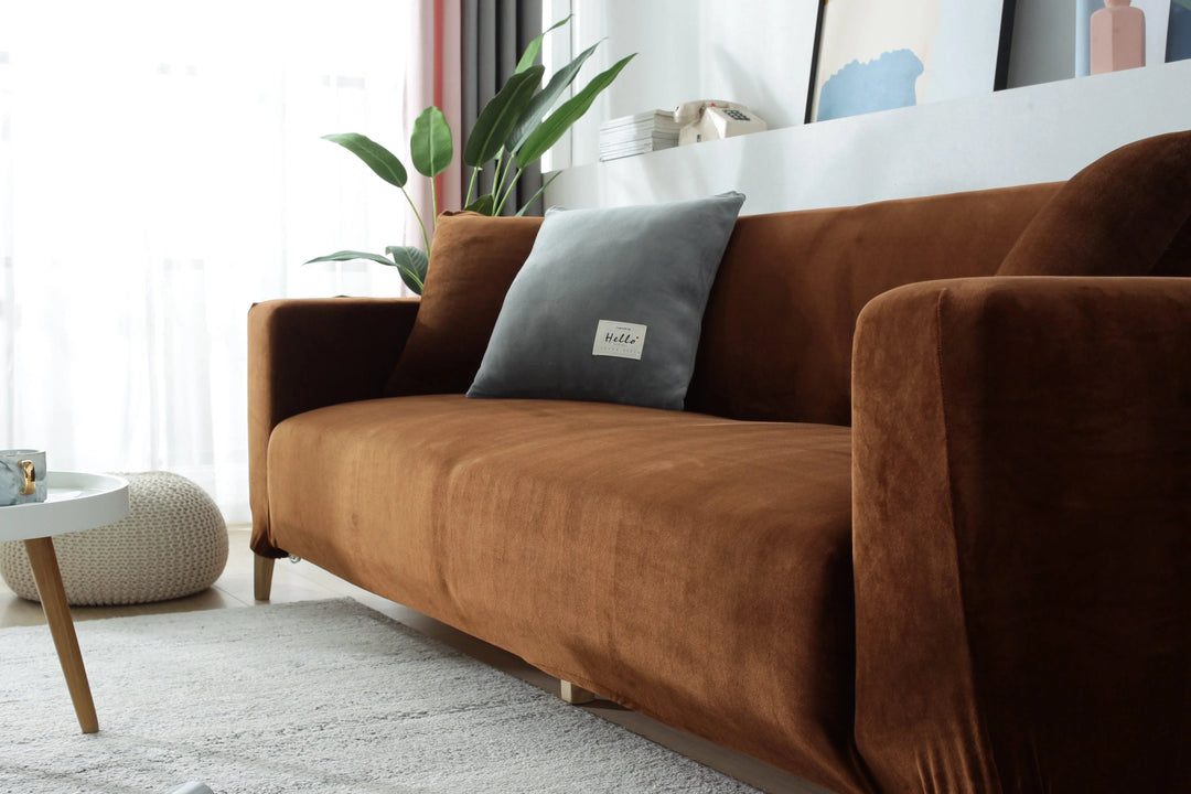 Brown velvet couch cover draped over a sofa, with a grey pillow.